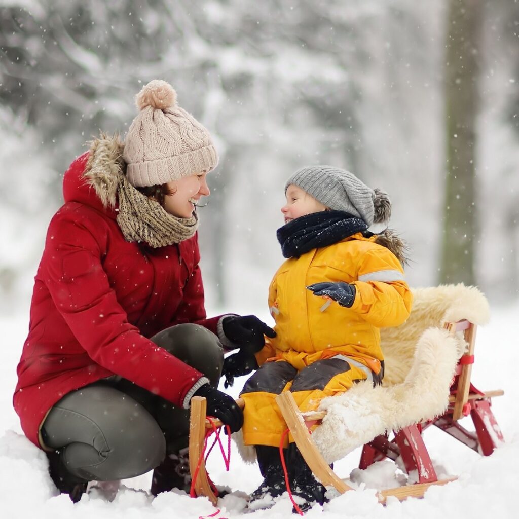 50 Amazing Winter Staycation Ideas - Woman with child on a sled