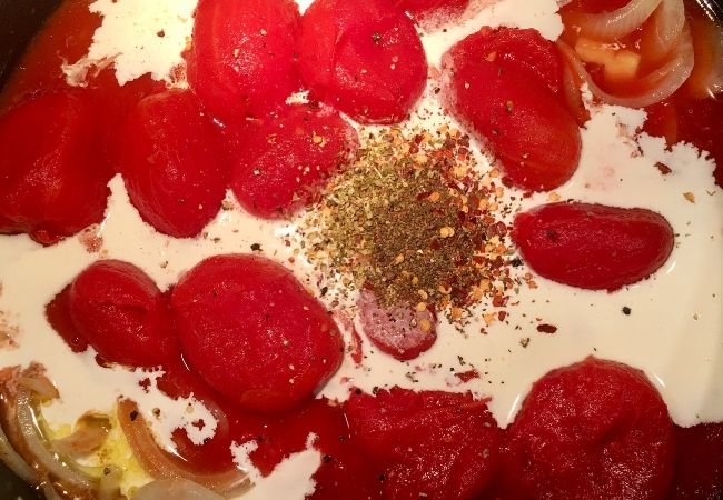 Ingredients for Creamy Tomato Soup simmering in a pot