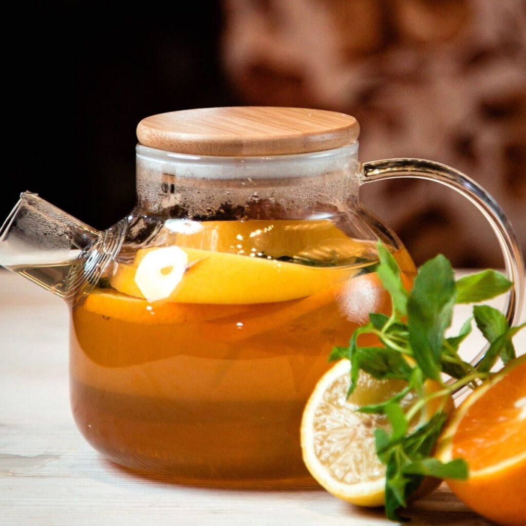 Cold Remedy Tea Recipe in a clear teapot with slices of oranges and lemons