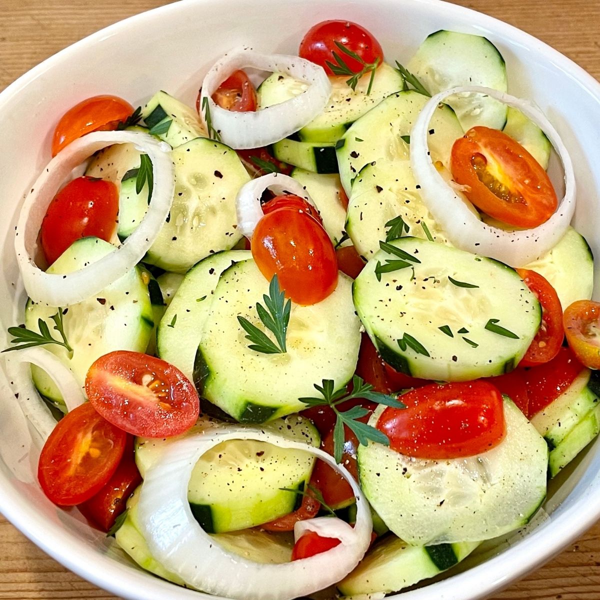 How to Make Cucumber Salad 2 Cucumbers sliced on a wooden surface.