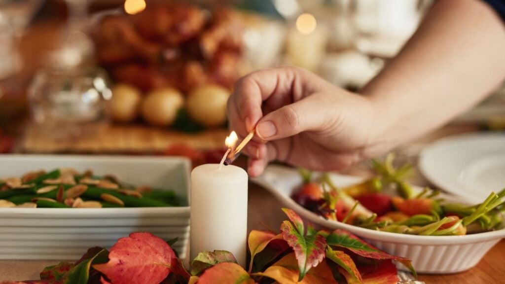 Intimate Family Dinners - Table with food and candle with hand lighting the candle