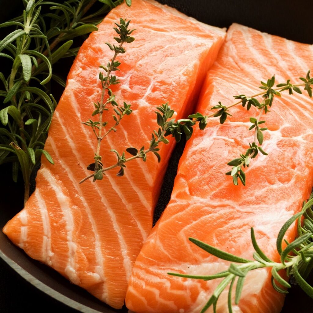 Raw salmon and fresh herbs in a cast iron skillet