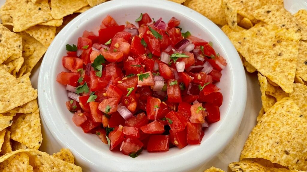 Recipe for Salsa Fresca in a white bowl surrounded by tortilla chips