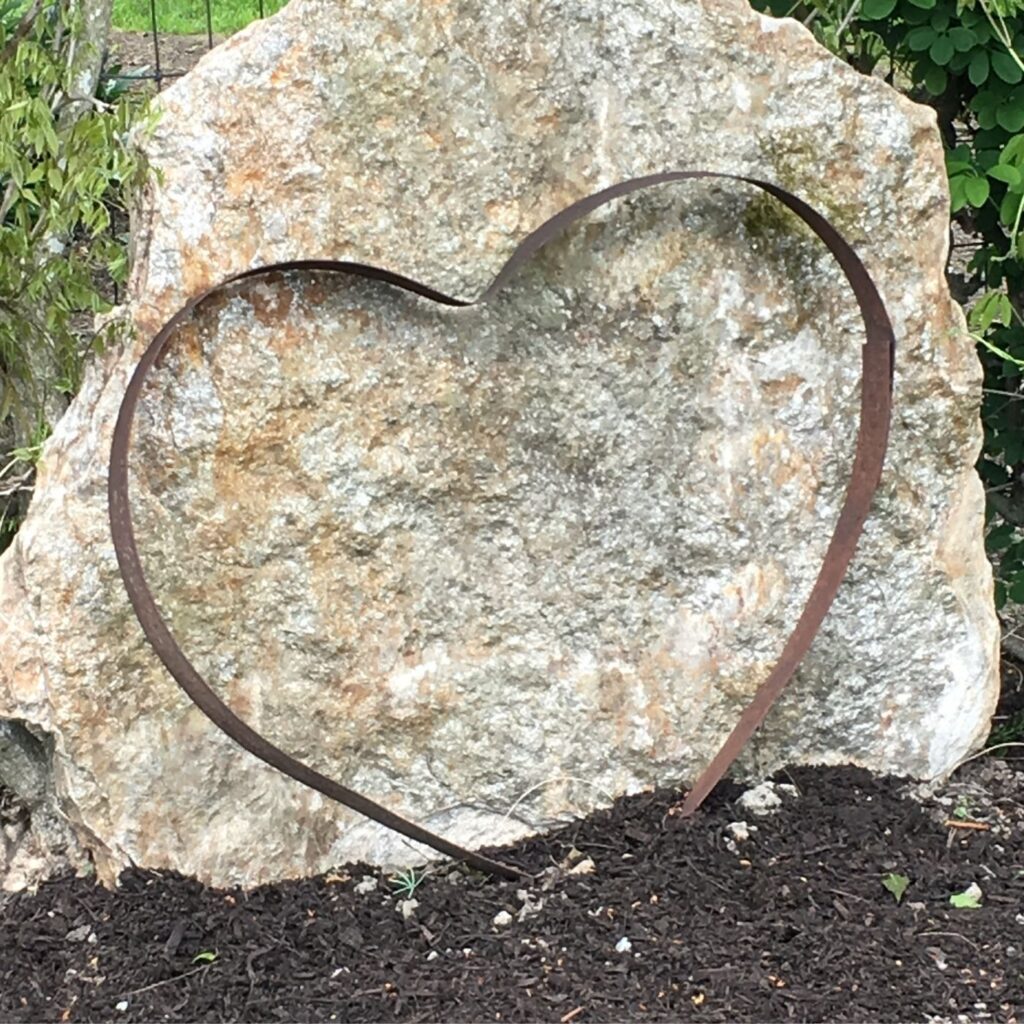 Rustic Garden Art - Love at Home - Metal Heart in front of a white rock