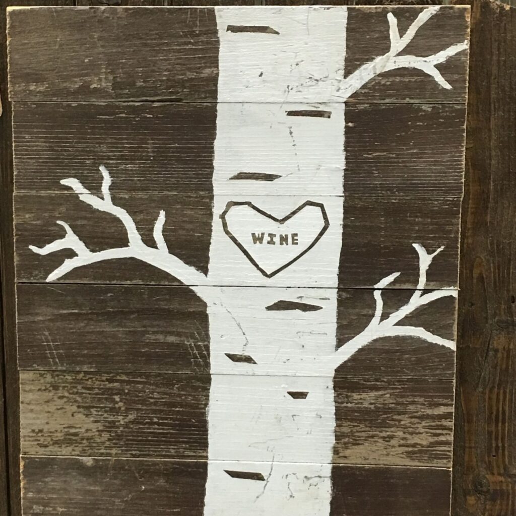 Rustic garden sign with the base of a tree with a heart and the word "wine" inside the heart.