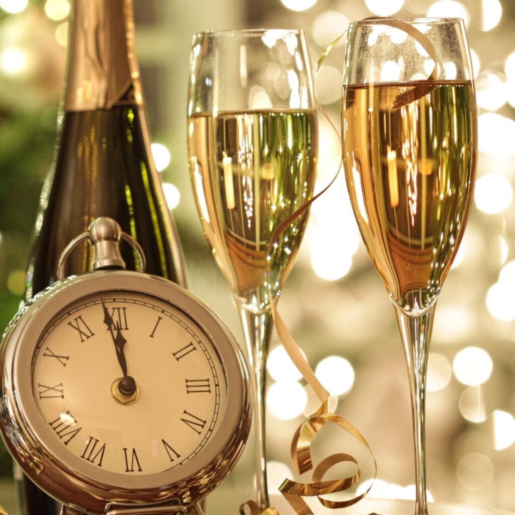 Hygge New Year Traditions - Bottle of champagne, two flutes of champagne, and clock.