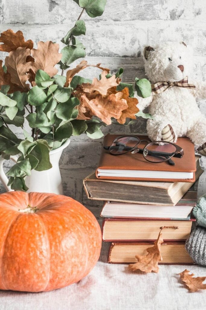 Fall Aesthetic Ideas - Photo of a Pumpkin, Fall Leaves, Stack of Books, and Teddy Bear