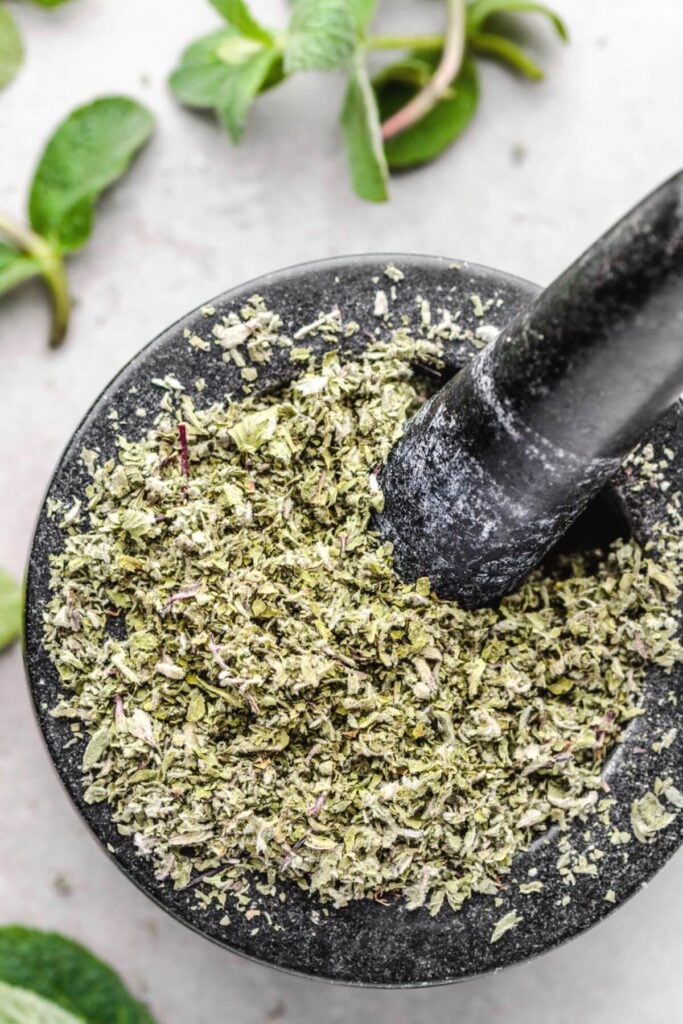 Dried mint leaves in a mortar and pestle after learning how to store mint