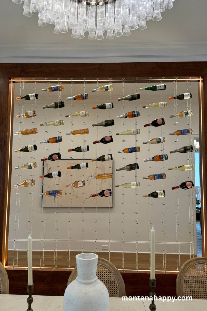 Modern Fun Home Decor Ideas - Modern Wine Wall - A dining room wall becomes a striking focal point with wine bottles suspended from sleek wires, creating a modern, airy partition that subtly defines the space. The hanging display adds both artistry and atmosphere, blending function with a touch of wine-cellar charm.