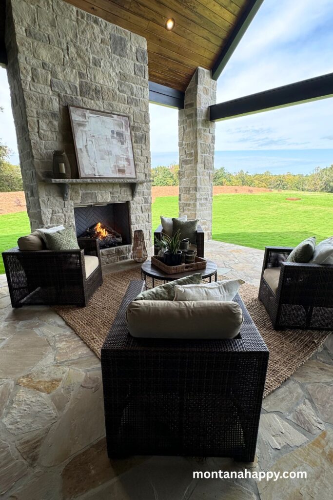 Modern Home Interiors - Modern Outdoor Patio Design -An outdoor stone patio with a glowing fireplace and four cozy chairs gathered around a round table creates an inviting space for relaxed conversation and cozy evenings outside.