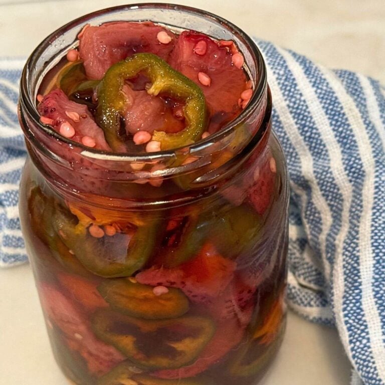 Photo of Quick Pickled Roasted Strawberry Jalapeños in a Mason Jar with a Blue and White Towel
