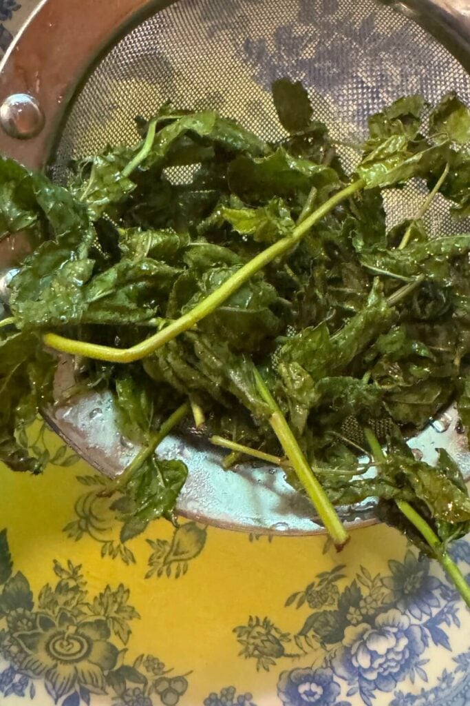 Photo of Mint being Strained from Mint Simple Syrup