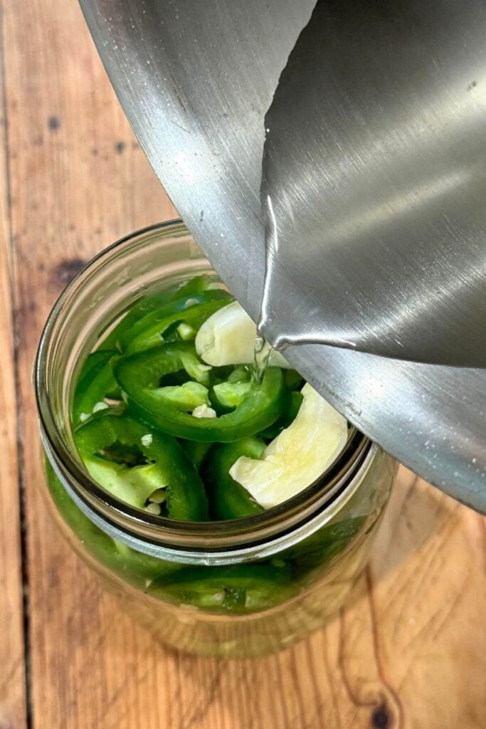 Quick Pickled JalapeƱos Recipe - Photo of JalapeƱo Brine being poured into JalapeƱo Slices